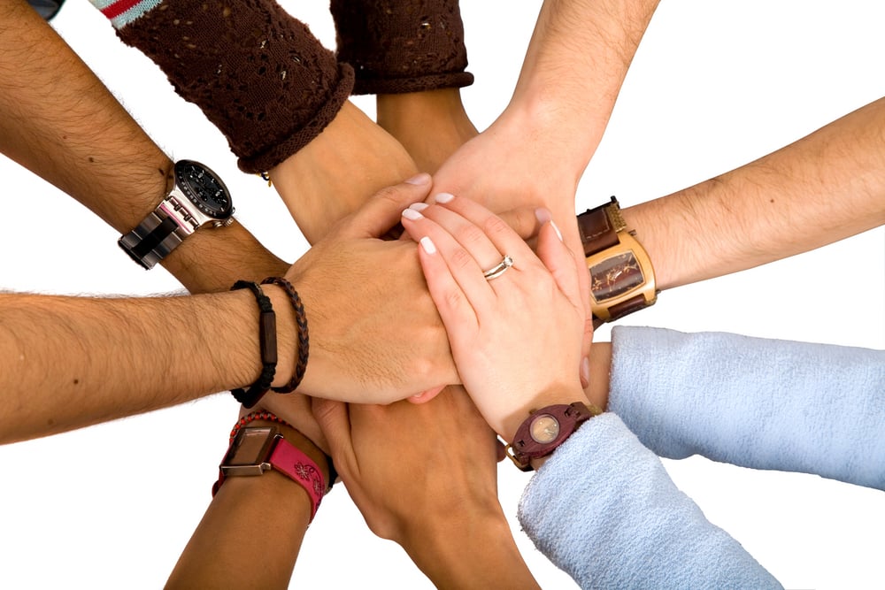 team with arms together in cooperation to look for success - isolated over a white background